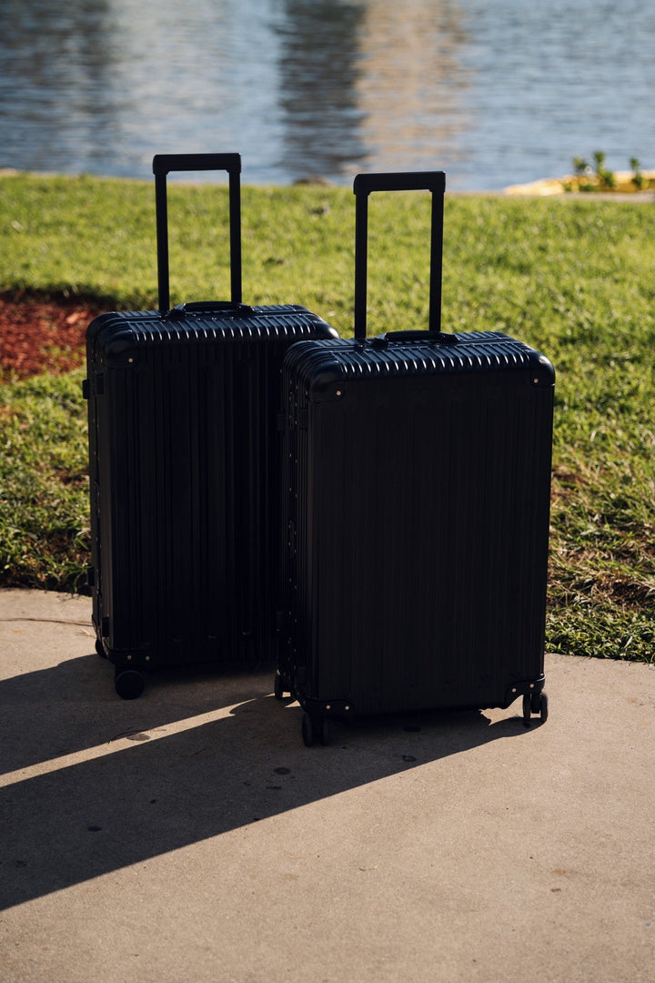 Two PREZOR suitcases in Graphite Black by the water