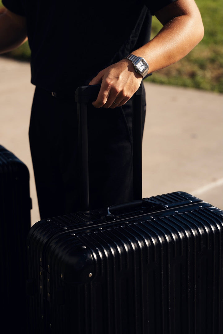 Hand on the telescopic handle of a PREZOR suitcase in Graphite Black