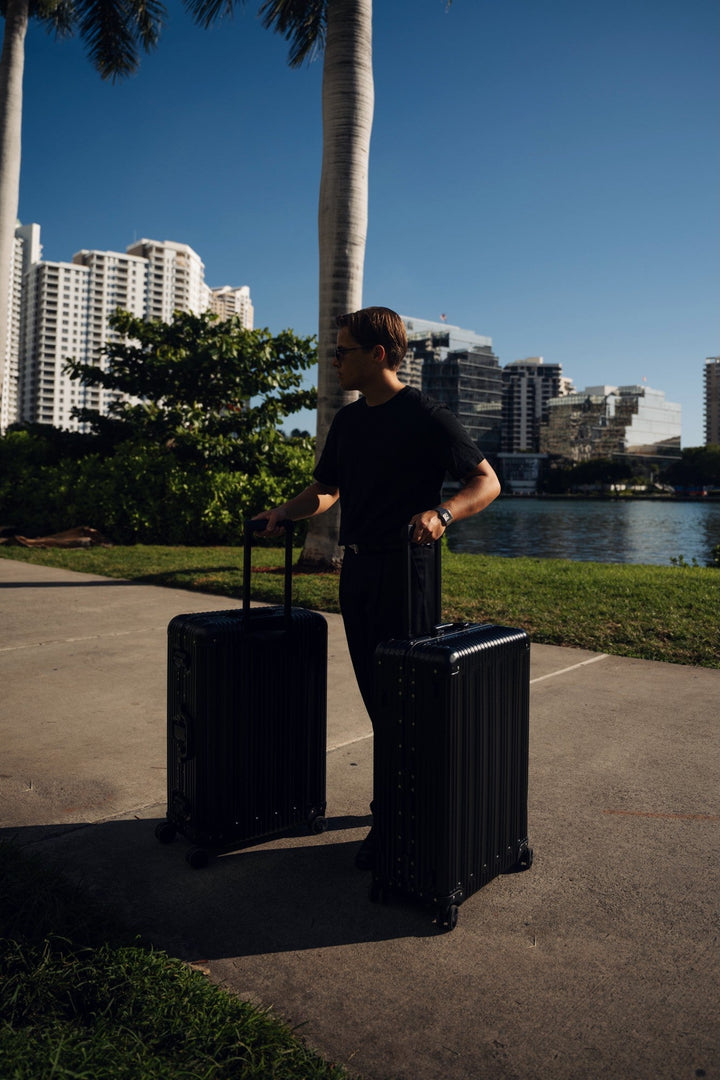 PREZOR suitcase in Graphite Black on a waterfront promenade in the evening light