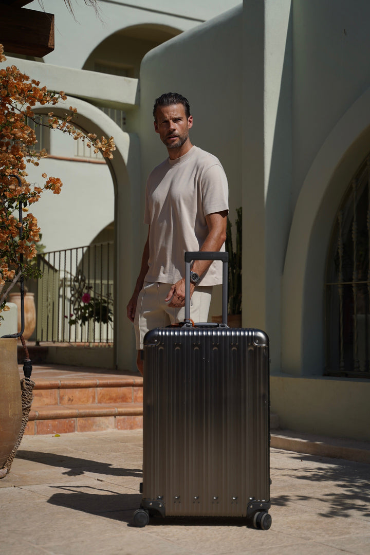 Traveler with a PREZOR suitcase in Metallic Grey outside a villa