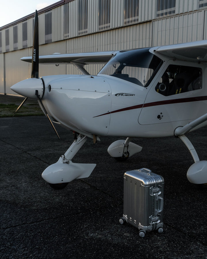 Silver PREZOR suitcase beside a private jet
